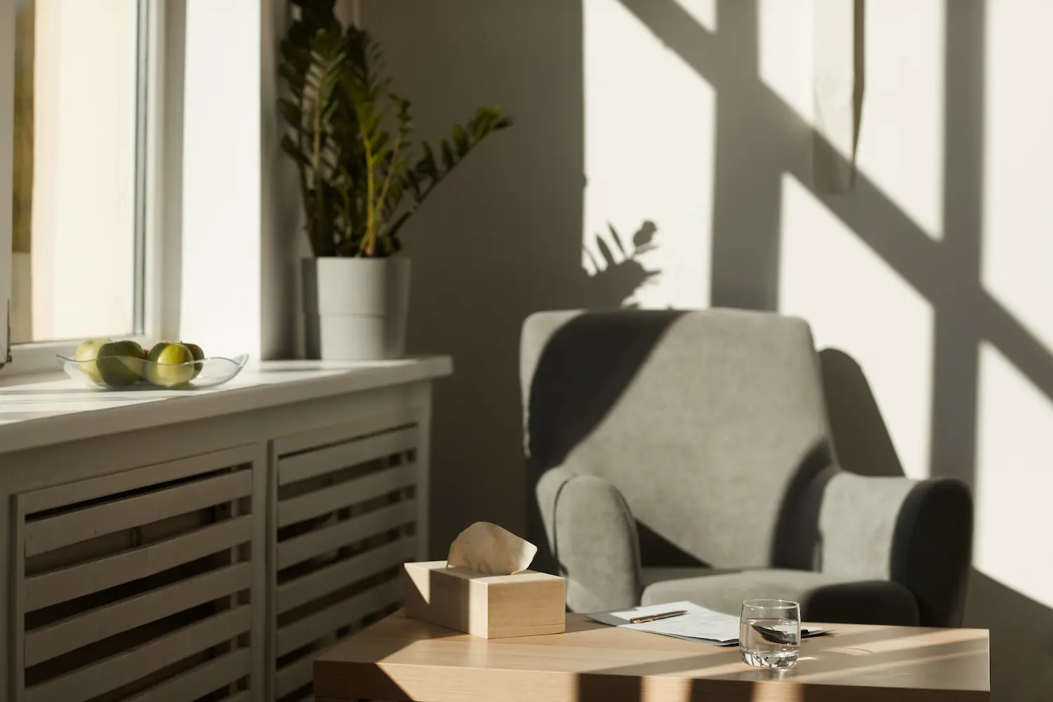 A quiet room with an empty armchair and soft daylight falling across the wall